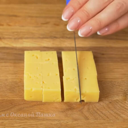 200 г российского сыра разрезаем сначала на пластинки толщиной примерно полтора сантиметра, а затем получившиеся пластинки нарезаем кубиками.