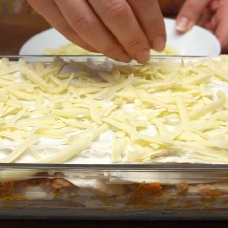Последний, верхний лаваш, смазываем сметаной и сверху посыпаем тертым сыром.
