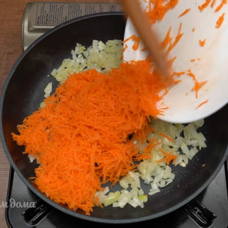 К луку добавляем тертую морковь. Пассеруем еще 2-3 минуты.