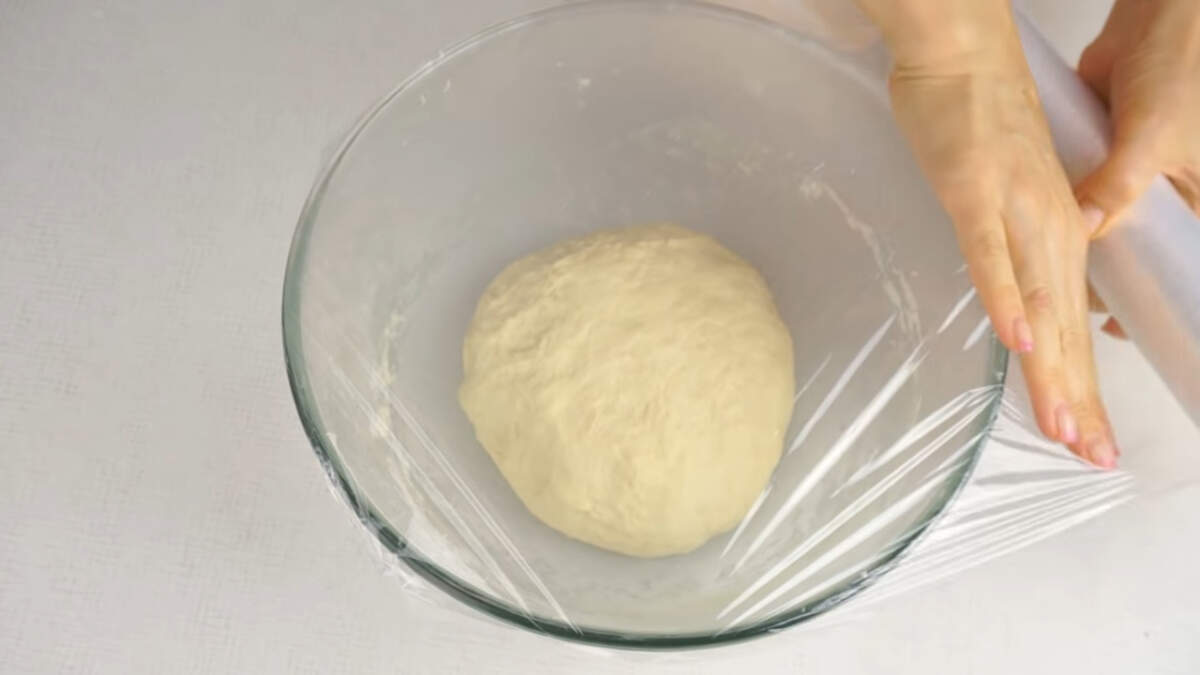 Готовое тесто собираем в шар, кладем в миску, накрываем пищевой пленкой и ставим в теплое место для того, чтобы оно подошло. Тесто должно увеличиться в объеме в полтора - два раза.
