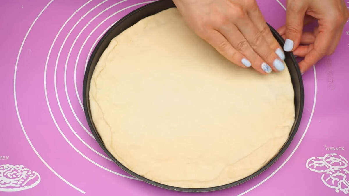Раскатанное тесто кладем в круглую форму для выпечки или сразу на противень. Дно формы или противень ничем смазывать не нужно. Если необходимо, то тесто растягиваем по форме руками. Толщина теста должна быть 1-2 мм.

