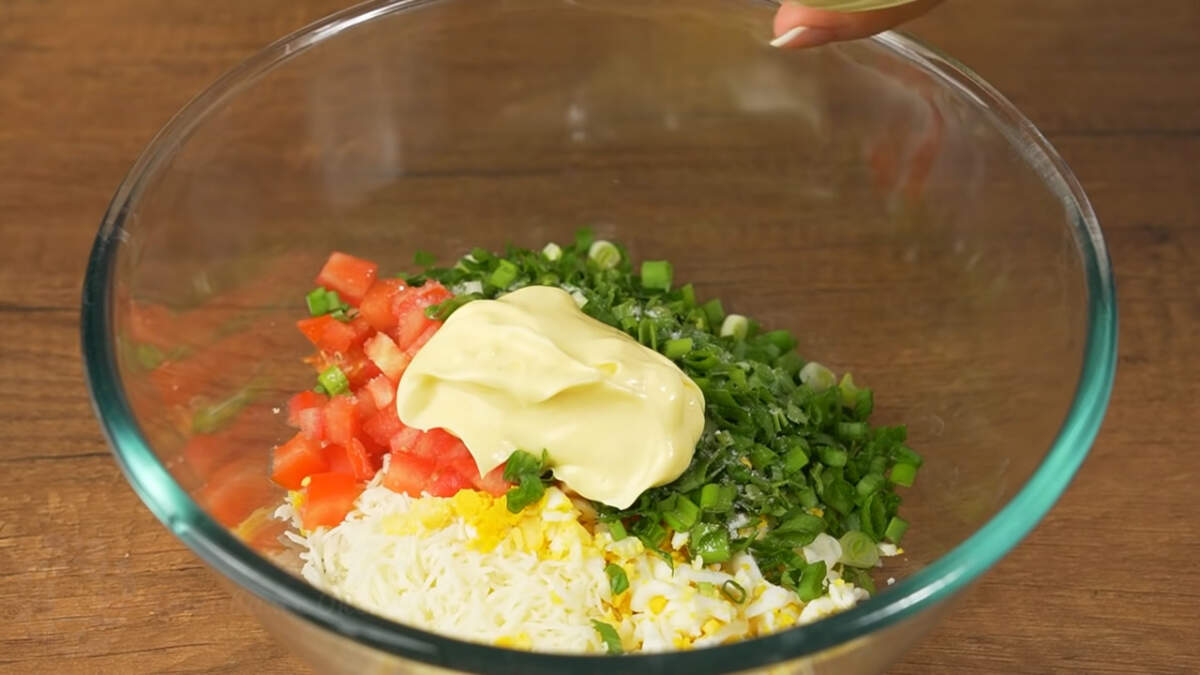 В миску кладем сыр, яйца, нарезанный помидор и  зелень. Все немного солим и заправляем примерно 1-2 ст. л. майонеза. Все перемешиваем.
