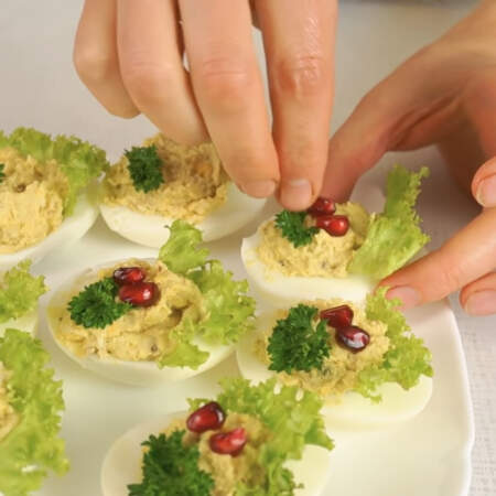 Фаршированные яйца украшаем листиками петрушки и для яркости украшаем зернами граната. 
