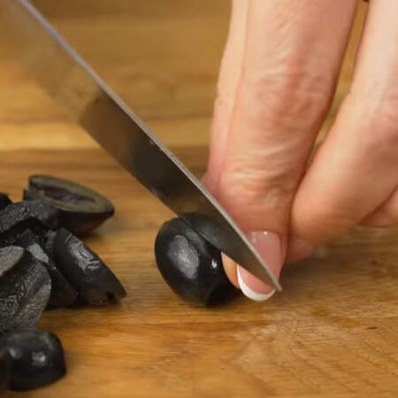 Берем примерно 400 г чёрных оливок без косточек и часть из них разрезаем пополам. 