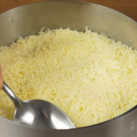 Следующим слоем выкладываем тертый сыр. Равномерно его распределяем и утрамбовываем ложкой.