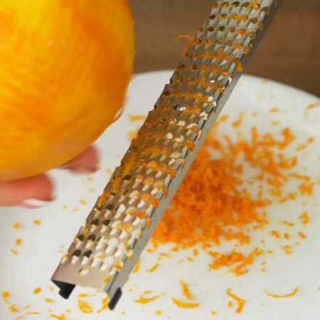 У одного апельсина снимаем цедру с помощью мелкой терки. Снимаем только оранжевую часть.