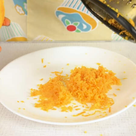 Сначала апельсин прокатываем по столу, придавливая руками, так легче будет выдавить из него сок. 
С апельсина снимаем цедру с помощью мелкой терки. Снимаем только ароматную оранжевую часть. 