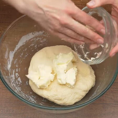 В уже вымешанное тесто добавляем 100 г мягкого, но не растопленного сливочного масла. Опять вымешиваем  тесто.