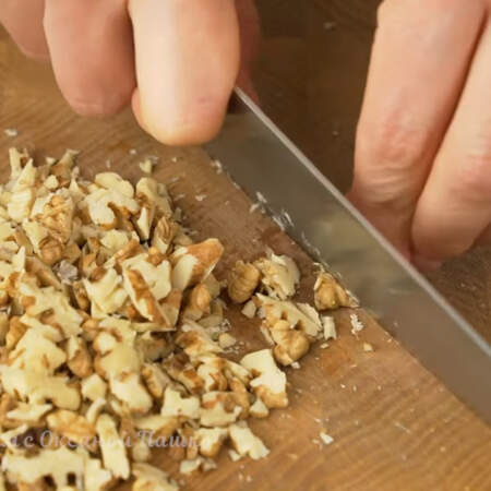60 г очищенных грецких орехов нарезаем ножом на небольшие кусочки.