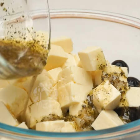 В миску высыпаем одну баночку зеленых оливок без косточек, сюда же добавляем одну банку маслин без косточек и нарезанный адыгейский сыр. Все поливаем приготовленной заправкой.