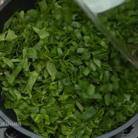На разогретую сковороду кладем небольшой кусочек сливочного масла. Сюда же выкладываем нарезанный шпинат и зеленый лук. 