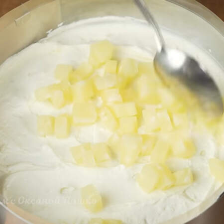 Кладем часть крема и распределяем его по коржу. Выкладываем нарезанные ананасы.
