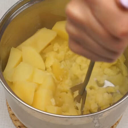 Картофель уже сварился, оставляем полстакана воды, в которой варился картофель, а остальную сливаем. Картофель хорошо разминаем картофелемялкой. 