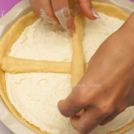 Выкладываем жгутики сверху на творожную начинку, разделяя ими пирог на 4 части.
