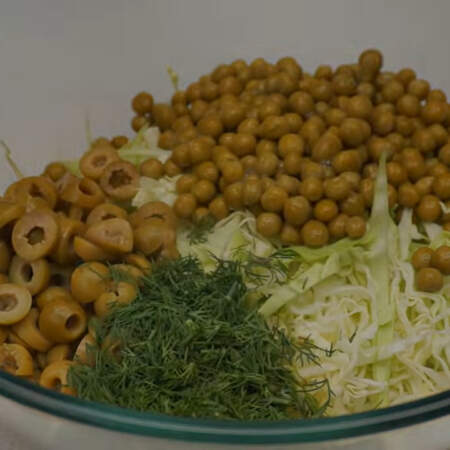 В миску кладем нашинкованную капусту, нарезанные оливки, банку консервированного горошка и порезанный укроп.