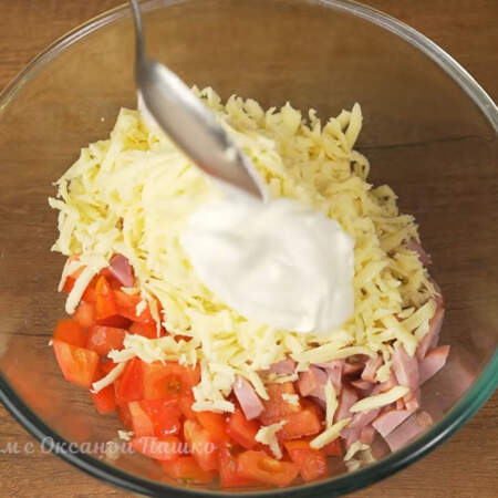 В миску насыпаем подготовленные помидоры, нарезанную ветчину и тертый сыр. Сюда же добавляем примерно 2 ст.л. сметаны.