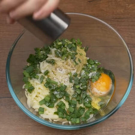 В миску кладем тертый картофель, сыр и зеленый лук. Сюда же разбиваем одно яйцо, все солим по вкусу и перчим.
