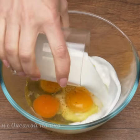 В миску разбиваем 4 яйца. Яйца солим по вкусу и перчим черным молотым перцем. Сюда же наливаем 100 мл молока. 