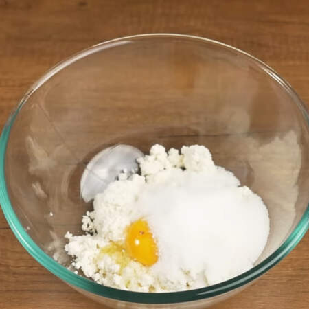 Сначала приготовим тесто.
В миску кладем 200 г творога, разбиваем 1 яйцо и насыпаем 3 ст. л. сахара.
