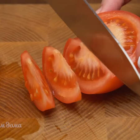 Берем один средний помидор разрезаем его пополам и вырезаем плодоножку. Половинки помидора нарезаем небольшими дольками.
