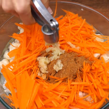 Прошло несколько минут, к капусте с маринадом добавляем подготовленную морковь. Сюда же насыпаем 30 г приправы для моркови по-корейски и сюда же выдавливаем через пресс примерно 6 зубчиков чеснока.