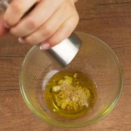 Готовим соус. В мисочку наливаем 2 ст.л. растительного масла, добавляем 1-2 ст. л. уксуса, выдавливаем через пресс 2 зубчика чеснока. Перчим черным молотым перцем.