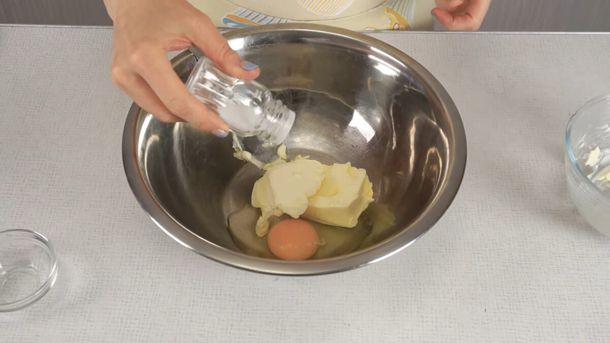 Размягченное сливочное масло выкладываем в миску, в которой будем замешивать тесто. Разбваем к нему 1 яйцо и добавляем щепотку соли. Все перемешиваем. 