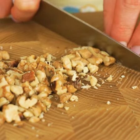 Орехи нарезаем ножом на более мелкие кусочки. 