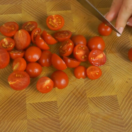 Примерно 150 г помидоров черри режем пополам и кладем в салат.