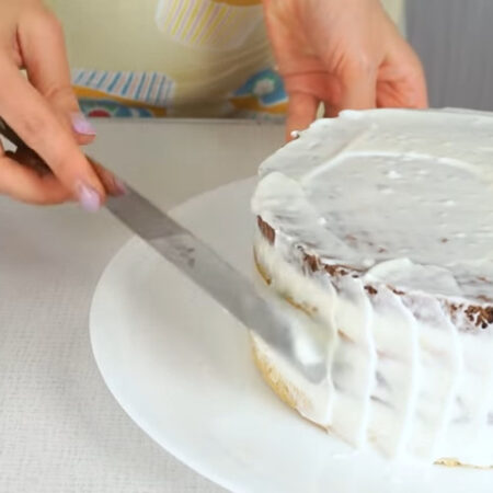 Охлажденный торт достаем из холодильника, переставляем на блюдо, на котором будем подавать его на стол. Оставшимся сметанным кремом обмазываем торт сверху и по бокам. 