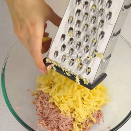 В миску к колбасе натираем 150 г сыра.