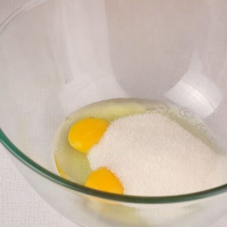 Сначала замесим тесто. В миску разбиваем 2 яйца и насыпаем сахар.