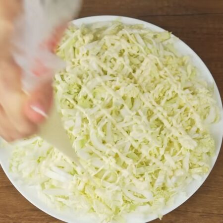 Складываем салат.
На большое круглое блюдо выкладываем пекинскую капусту. Равномерно ее распределяем. Капусту немного солим. Наносим сеточку из майонеза.