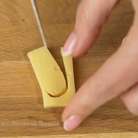 Теперь займемся украшением.
Сыр нарезаем толстыми пластинками. Из пластинки сыра ножом вырезаем ушко кролика.