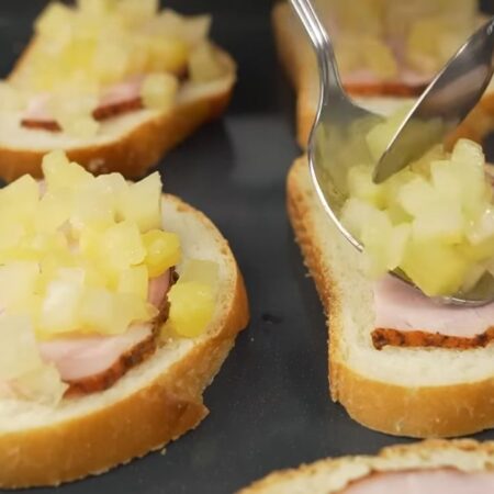 Складываем бутерброды.
Ломтики батона выкладываем на противень от духовки.
На каждый кусочек батона кладем нарезанную буженину.
Сверху выкладываем кусочки ананаса.