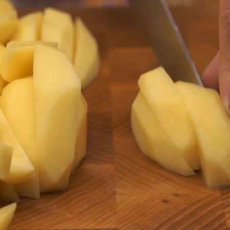 Пока маринуются ребрышки подготовим картошку. 1,5 кг картофеля чистим и нарезаем дольками. Нарезанный картофель перекладываем в форму для запекания, смазанную растительным маслом. 