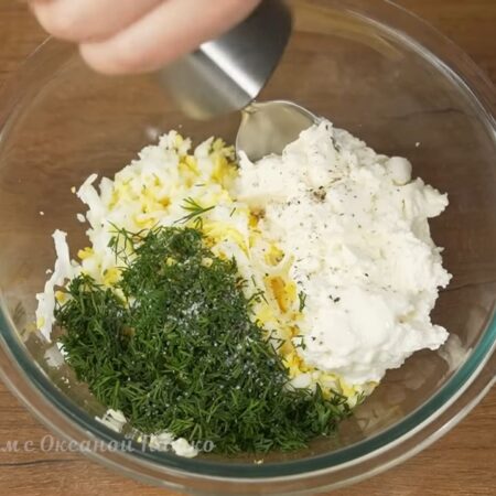 Подготовленный укроп добавляем к яйцам. Сюда же добавляем 200 г плавленного сыра. Я использую сыр Янтарь. Все немного солим и перчим черным молотым перцем.