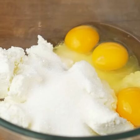 Сначала приготовим тесто.
В миску кладем 300 г творога, насыпаем 150 г сахара и 1/2 ч. л. ванильного сахара. Сюда же разбиваем 3 яйца. 