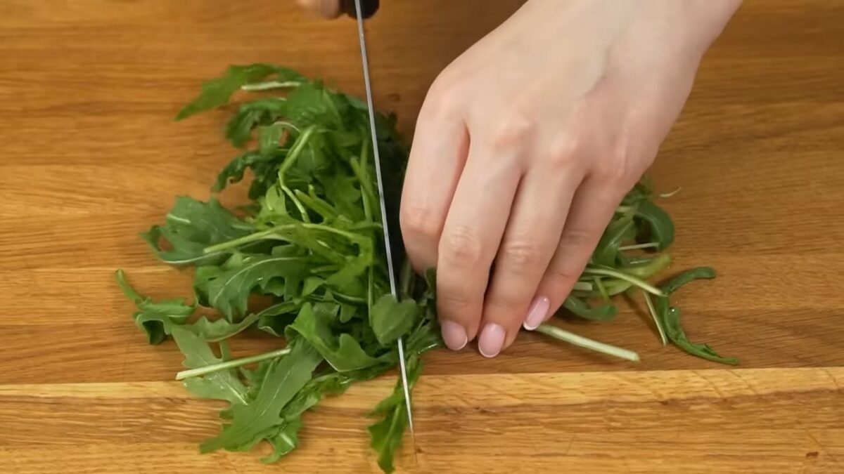 Сначала подготовим ингредиенты.
Пучок листьев рукколы разрезаем пополам, чтоб было удобнее брать салат.
