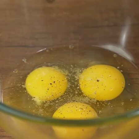 Три яйца разбиваем в миску. Немного солим и перчим черным молотым перцем. 