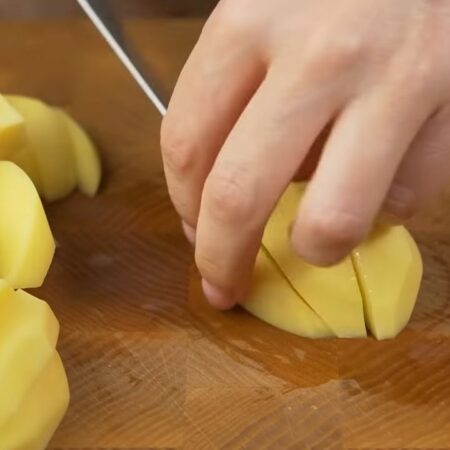 Примерно 1 кг картофеля чистим от кожуры и моем. Картошку разрезаем сначала пополам, а затем каждую половинку и нарезаем дольками.