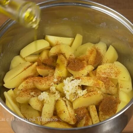 Картошку солим по вкусу, насыпаем 1 ст.л. приправ для картофеля или можно просто посыпать сладкой молотой паприкой. Перчим черным молотым перцем. Добавляем через пресс 2-3 зубчика чеснока. Наливаем 2-3 ст.л. растительного масла. 