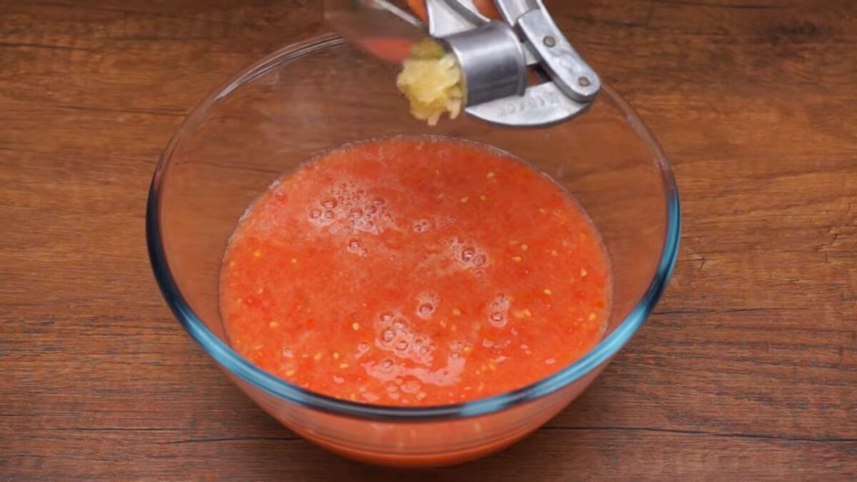 В томатную массу немного солим. Сюда же выдавливаем через пресс 1 зубчика чеснока. Перчим по вкусу. Все перемешиваем.