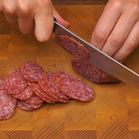 100 г колбасы нарезаем тонкими пластинками. Колбасу можно использовать любую или заменить отварным мясом.