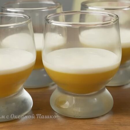 Примерно половину приготовленной сметанной смеси разливаем по стаканчикам на уже застывший апельсиновый слой.