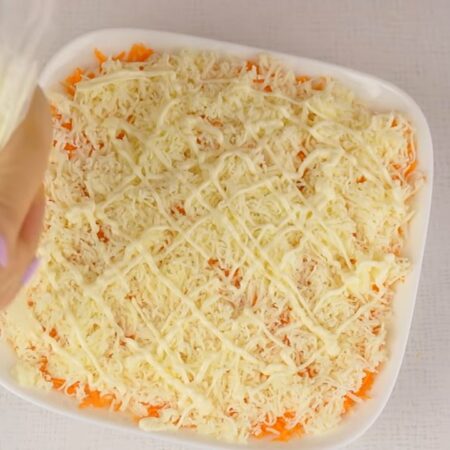 Сверху на морковь кладем половину тертого сыра.
Наносим сеточкой майонез.