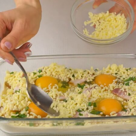 Вокруг яиц выкладываем оставшийся бекон, лук и сыр. 