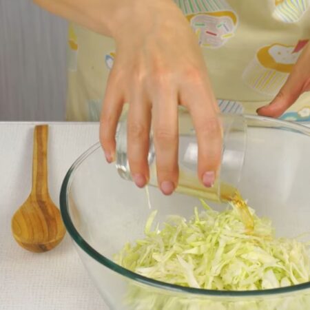 Нашинкованную капусту перекладываем в большую миску. Капусту солим по вкусу и добавляем 1 ст. л. уксуса. Все перемешиваем и отставляем. Пока будем подготавливать остальные ингредиенты, капуста промаринуется. 