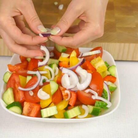 Перемешанные овощи перекладываем в салатник, в котором он будет подаваться на стол. Нарезанный лук выкладываем сверху на овощи. 