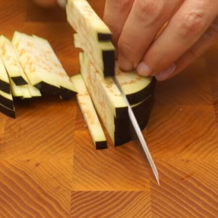 Полкилограмма баклажанов нарезаем сначала кружочками, а затем кружочки разрезаем на брусочки.